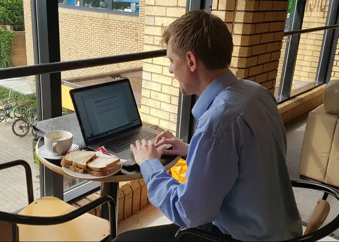 Working at a laptop with a bacon sandwich